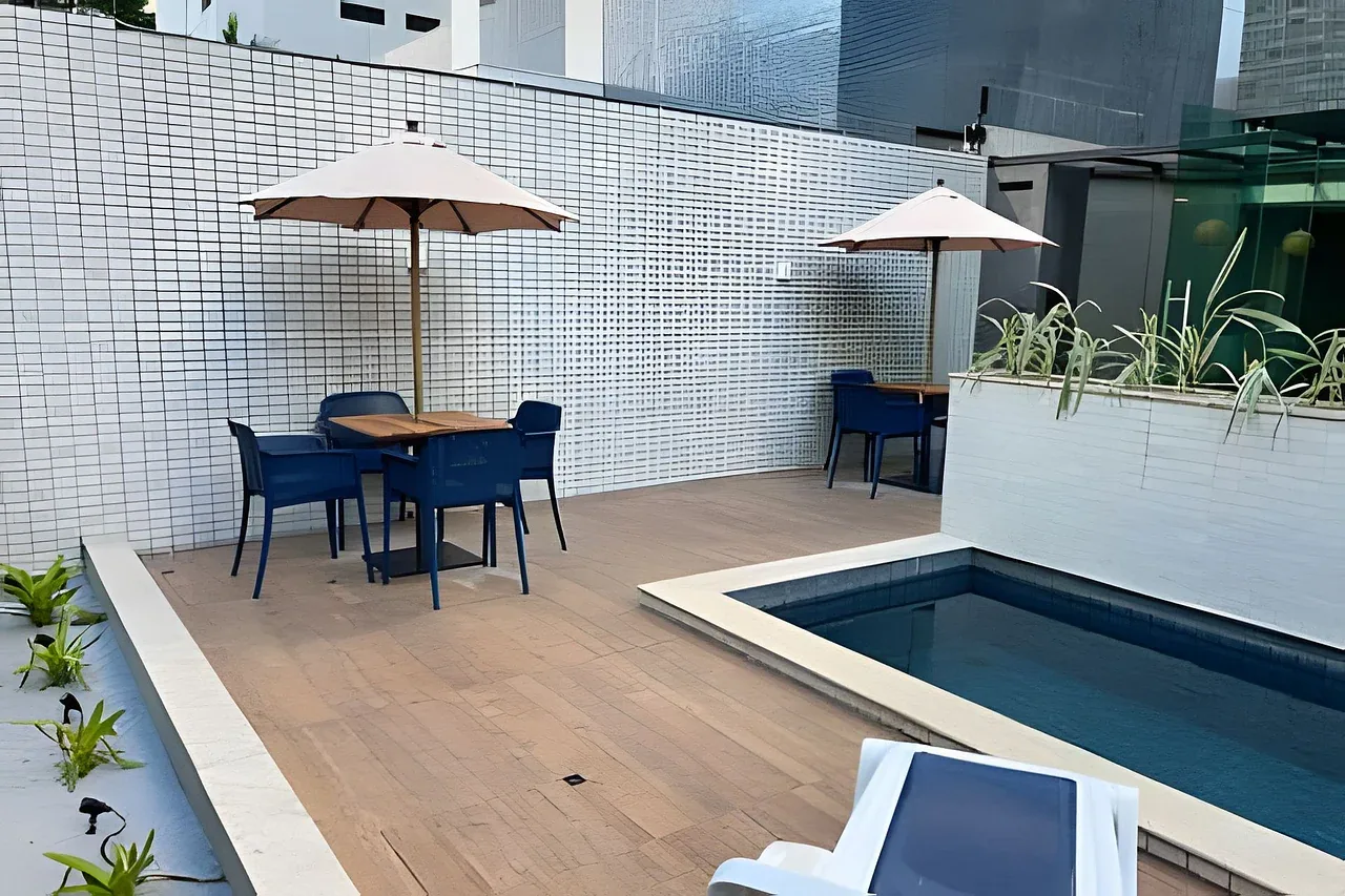 Deck da piscina com guarda-sóis e mesas