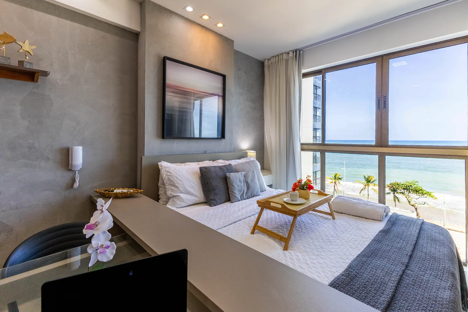 Cama, TV e janela com vista para o mar