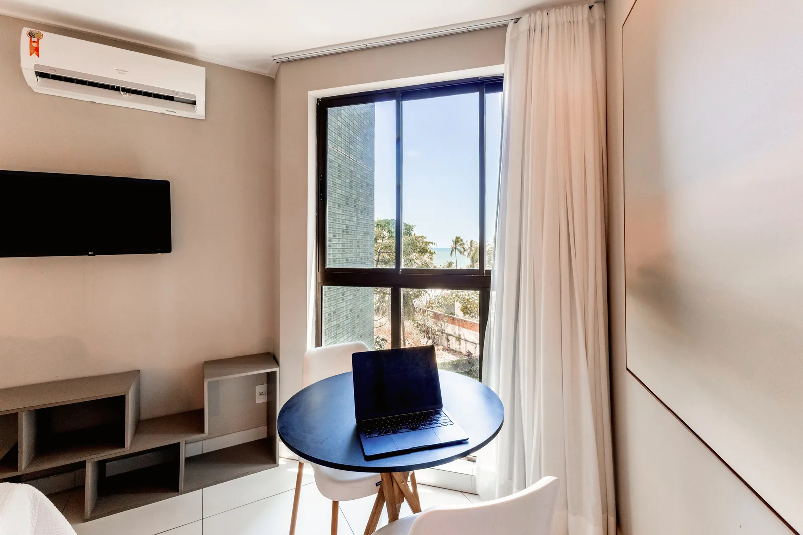 TV, mesa e janela com vista para o mar